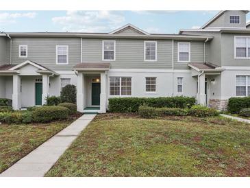 Two-story townhome with green siding, landscaping, and a walkway at 2804 Grasmere View Pkwy, Kissimmee, FL 34746