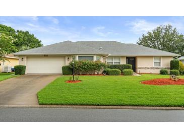 Charming single-story home with a well-manicured lawn, beautiful landscaping, and an attached two-car garage at 27100 Racquet Cir, Leesburg, FL 34748