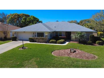 Charming single-story home featuring a manicured lawn, mature landscaping, and a welcoming facade at 27100 Racquet Cir, Leesburg, FL 34748