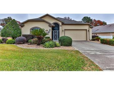 Tan one-story house with landscaped yard, attached garage, and driveway at 706 Lake Diamond Ave, Ocala, FL 34472