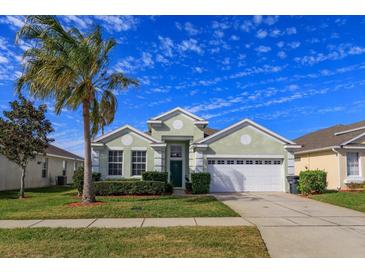 Single-story house with green exterior, palm tree, and two-car garage at 2254 Wyndham Palms Way, Kissimmee, FL 34747