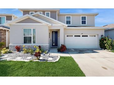 Two-story house with a two-car garage, landscaping, and stone accents at 1076 Sugarwood St, Davenport, FL 33837