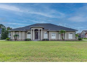 Large one-story home with a stucco exterior, landscaped lawn, and a three-car garage at 164 Sunrise Hill Ln, Auburndale, FL 33823
