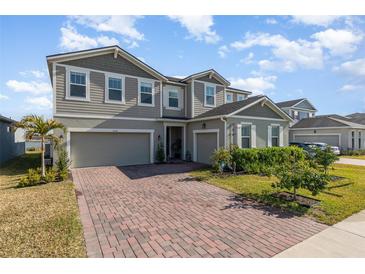 Charming two-story home featuring a brick driveway, well-manicured lawn, and inviting curb appeal at 3200 Canna Lily Pl, Clermont, FL 34711