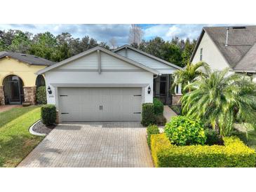 Single-story home with gray garage door and landscaped front yard at 108 La Cresta Ct, Davenport, FL 33837