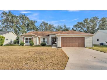 Inviting exterior of a single-story house with a brown garage door and well-manicured lawn at 4064 River Crest Cir, Leesburg, FL 34748