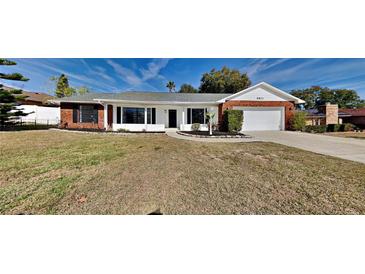 Brick ranch house with a white front door, attached garage, and well-manicured lawn at 6821 Rembrandt Dr, Orlando, FL 32818