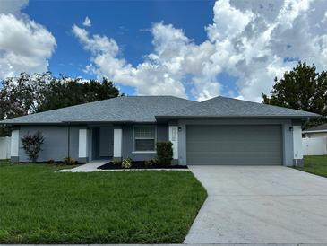 Newly constructed home with gray exterior, attached garage, and landscaped lawn at 5349 Hidden Oaks Dr, Lakeland, FL 33811