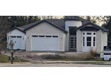 Newly constructed home with stone exterior, three-car garage, and landscaping at 101 Hallmark Ct, Lake Mary, FL 32746