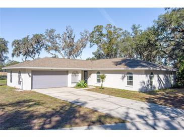 Single-story home with a grey garage door and a paved driveway at 135 Country Club Ln, Mulberry, FL 33860