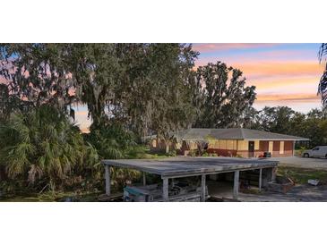 Lakeside home featuring a boat dock, single-story structure, and mature trees draped in Spanish moss at 8309 W Lake Marion Rd, Haines City, FL 33844
