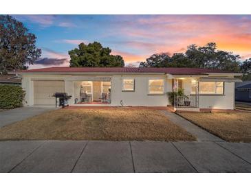 Charming single-story home featuring a red metal roof and well-maintained front lawn under a colorful evening sky at 11213 Se 53Rd Ct, Belleview, FL 34420