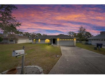 Charming one-story home with a well-manicured lawn and a long driveway under a colorful, cloudy sky at 1060 Colony Park Dr, Lakeland, FL 33813