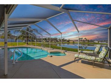 A screened-in pool and hot tub are located next to a lake, offering outdoor enjoyment at any time of day at 8867 Pebblebrooke Dr, Lakeland, FL 33810