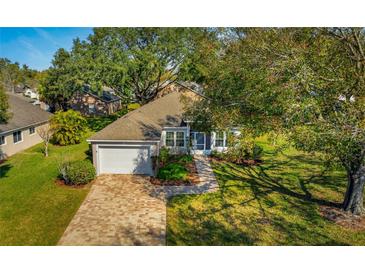 Charming home with a brick driveway, attached garage, mature landscaping, and well maintained lawn at 2450 Shelby Ln, Clermont, FL 34711