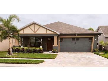 One-story home with gray siding, brown roof, and a paved driveway at 309 Burrowing Owl Ln, Winter Haven, FL 33880