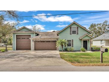 Charming green home with a well-manicured lawn, multiple garages, and stone accents at 506 Parrott Rd, Auburndale, FL 33823