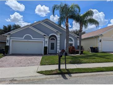 Charming single-story home featuring a two-car garage and mature landscaping, including palm trees at 131 Vine Dr, Davenport, FL 33837
