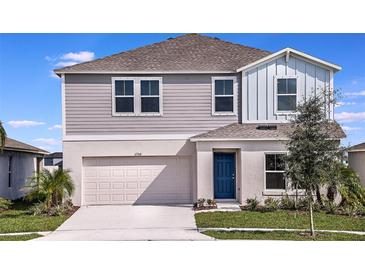 Charming two-story home with gray siding, a blue front door, well-manicured lawn, and an attached two-car garage at 1600 Ellesmere Ave, Haines City, FL 33844