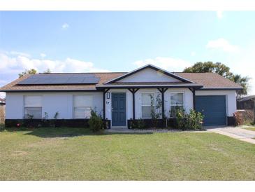 Charming single-story home featuring solar panels, a covered front porch, and a well-maintained lawn at 17 Trotters Cir, Kissimmee, FL 34743