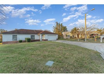 A single-story home with a white exterior, a well-maintained lawn, and an attached garage at 3290 Big Valley Dr, Lakeland, FL 33812