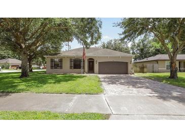 Charming single-story home featuring a well-manicured front lawn, two-car garage and inviting front door at 416 Country View Cir, Deland, FL 32720