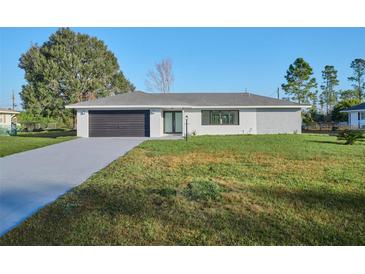 Charming single-story home with a well-maintained lawn and modern garage at 2310 Laguna Dr, Indian Lake Estates, FL 33855