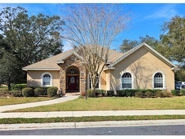 Charming single-story home featuring a stone-accented entrance, arched windows and lush landscaping at 5685 Lake Victoria Dr, Lakeland, FL 33813
