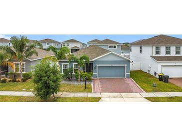 Charming single-Gathering home with a well-manicured lawn, palm trees, and a brick driveway at 648 Bloom Ter, Davenport, FL 33836