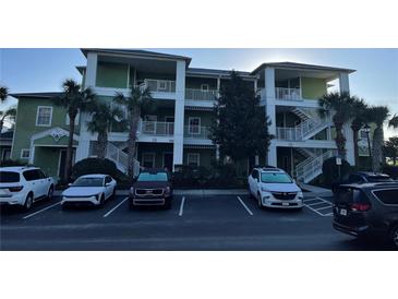 Three-story building with green facade, white railings, palm trees, and a parking lot in front at 705 Gran Bahama Blvd # 705, Davenport, FL 33897