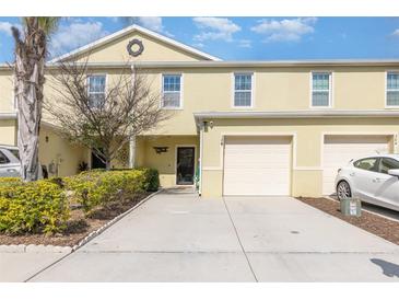Two-story townhome with one-car garage, well-kept lawn, and yellow siding at 380 Arbor Lakes Dr, Davenport, FL 33896