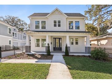 Inviting two-story white home boasts a manicured lawn, walkway, covered porch, and a welcoming entrance at 2308 Depauw Ave, Orlando, FL 32804