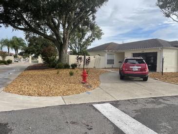 Charming one-story home featuring a well-manicured front yard with mature trees and a cozy driveway at 1353 Lajolla Cir, The Villages, FL 32159