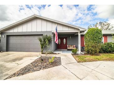 Charming single-story home featuring a gray brick facade, landscaped front yard and an American flag by the front door at 4739 Tierra Alta Ct, Lakeland, FL 33813