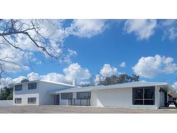 Wide angle view of the single story home, with a silver roof, bright white paint, and a well manicured yard at 1912 Providence Rd, Lakeland, FL 33805