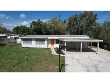 Charming single-story home with a carport, tidy landscaping, and a bright orange front door at 1625 Avenue D Ne, Winter Haven, FL 33881