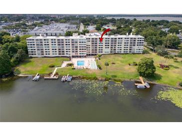 Waterfront condominium with a beautiful pool, boat docks, and lush landscaping with mature trees and green grass at 700 Mirror Nw Ter # 505, Winter Haven, FL 33881