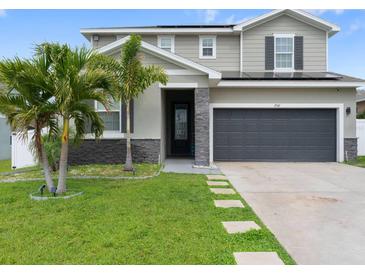 Beautiful two-story home with stone accents, gray siding, and a well-manicured lawn with palm trees at 1741 Hill Top Dr, Dundee, FL 33838