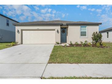 Charming single-story home with a two-car garage and a well-manicured front lawn at 1006 Oak Valley Dr, Auburndale, FL 33823