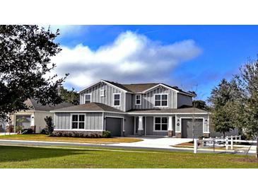 Beautiful two-story home featuring gray siding, a well-manicured lawn, and a three-car garage at 6488 Sw 78Th Ct, Ocala, FL 34474