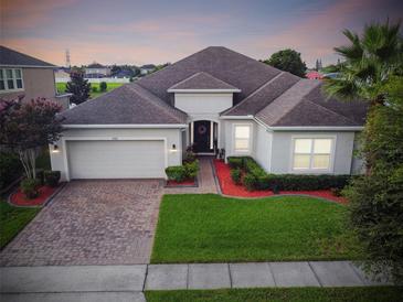 Charming one-story home with a manicured front lawn, brick driveway, and attached two-car garage at 2163 Plantation Oak Dr, Orlando, FL 32824