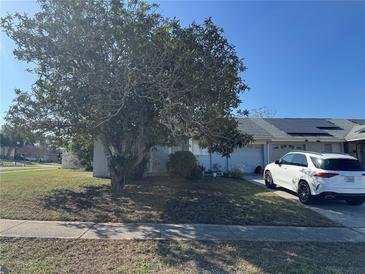 Charming home with a well-maintained lawn, mature tree and a white SUV parked in the driveway at 89 Winter Ridge Cir, Orlando, FL 32835