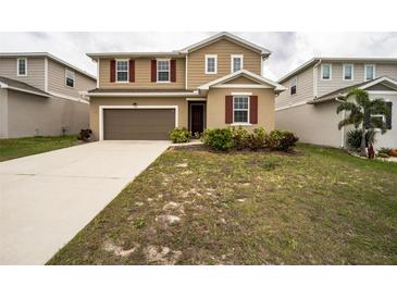 Two-story home with tan siding, red shutters, a brown garage door, and a well-manicured front lawn at 348 Lake Smart Cir, Winter Haven, FL 33881