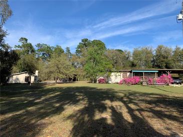 Sprawling front yard showcasing the house, carport, secondary structure, and mature trees at 24605 Ne 177Th Ter, Fort Mc Coy, FL 32134