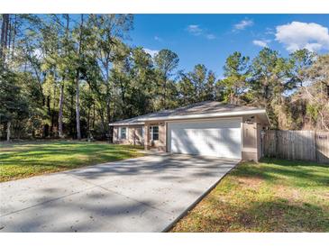 Charming single-story home featuring an attached two-car garage and a long driveway in a verdant, wooded setting at 4111 Se 131St Ln, Belleview, FL 34420