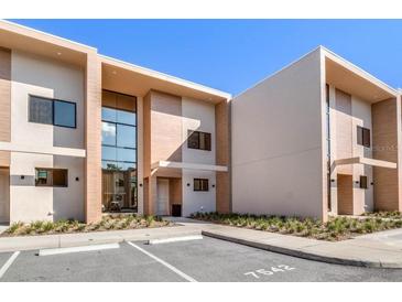 Modern townhouse exterior with large windows and neutral color scheme against blue sky at 7540 Brooklyn Dr, Kissimmee, FL 34747