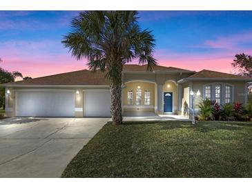 Charming single-story home featuring a lush front yard, a three car garage, and a welcoming blue front door at 113 Grand Reserve Ct, Davenport, FL 33837