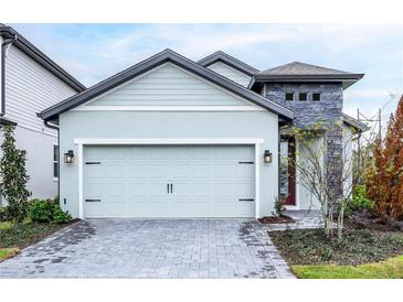 Attached two-car garage featuring a modern door, exterior lights and a stone facade at 7721 Somersworth Dr, Kissimmee, FL 34747