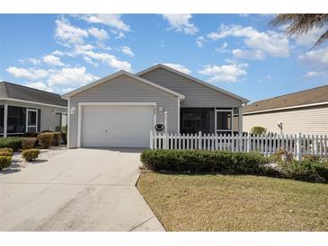 Charming single-story home with a well-manicured lawn and white picket fence offers curb appeal at 1654 Indigo Ave, The Villages, FL 32162
