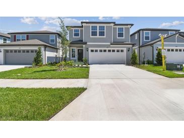 Two-story home with gray siding, lush lawn, and a concrete driveway leading to a two-car garage at 284 Woodsage Pl, Lake Alfred, FL 33850